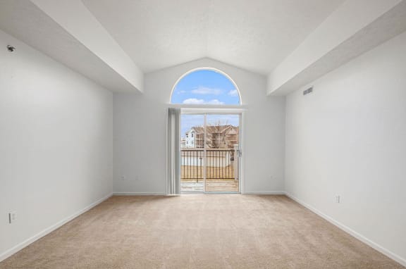 living room with a cathedral ceiling and a door to a balcony  at Black Sand Apartment Homes, Nebraska, 68504