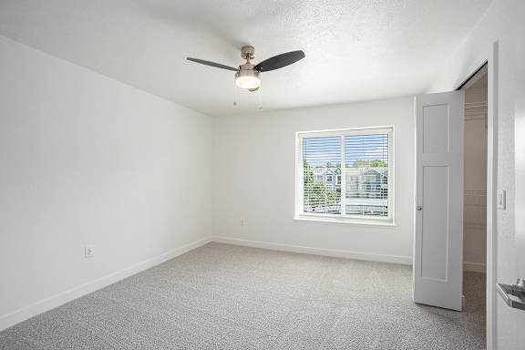 A bedroom with a large window and ceiling fan at Byron Lakes Apartments, Byron Center, 49315