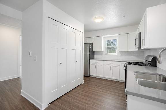 A kitchen with white cabinets and a hard-surface floor at Byron Lakes Apartments, Michigan, 49315