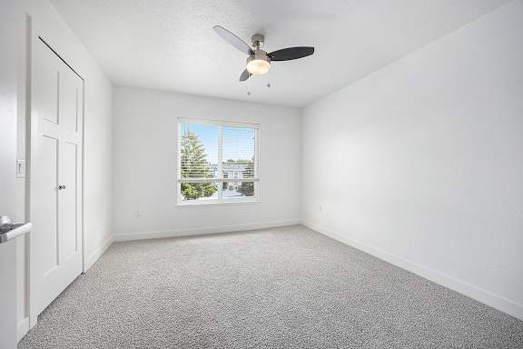 a bedroom with a ceiling fan and a window at Byron Lakes Apartments in Byron Center, MI