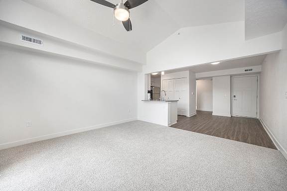 A dining room with a cathedral ceiling, ceiling fan and a carpeted floor at Byron Lakes Apartments in Byron Center, MI