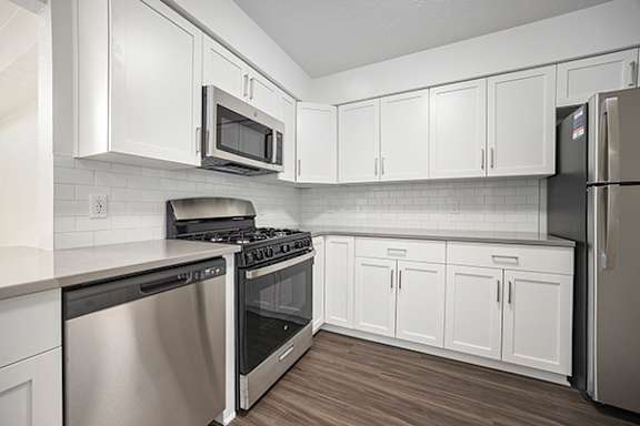 A kitchen with white cabinets and stainless steel appliances at Byron Lakes Apartments in Byron Center, MI