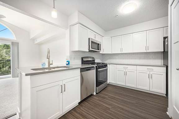 a kitchen with white cabinets and stainless steel appliances at Byron Lakes Apartments in Byron Center, MI