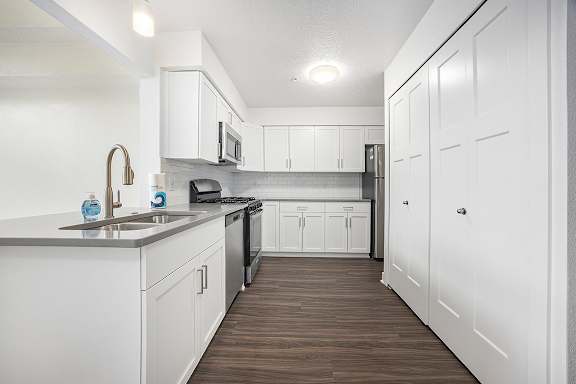 A kitchen with white cabinets and a hard-surface floor at Byron Lakes Apartments in Byron Center, MI