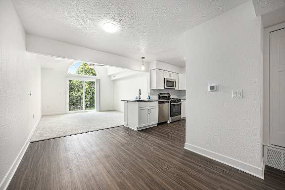 A kitchen and living room with a cathedral ceiling and a window to a balcony at Byron Lakes Apartments, Byron Center, MI