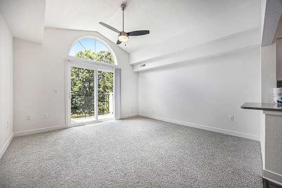 A living room with a ceiling fan and carpeted floor at Byron Lakes Apartments, Byron Center, MI
