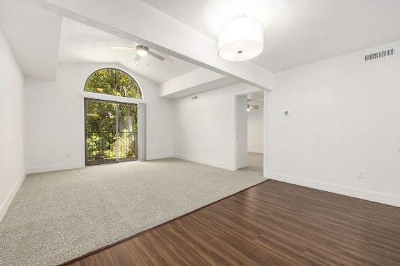 living room with cathedral ceiling and slider to private balcony at Byron Lakes Apartments, Byron Center, MI