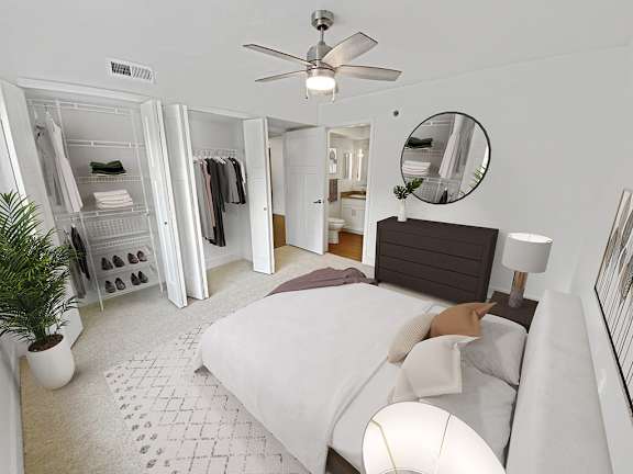 A master bedroom with a bed, a ceiling fan, a large closet and attached bath at Byron Lakes Apartments, Michigan, 49315