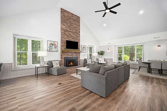 A community room with a fireplace and a grey couch at Byron Lakes Apartments in Byron Center, MI