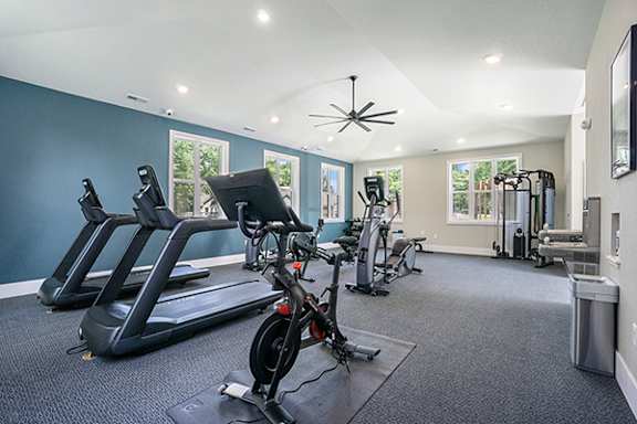 A fitness center with treadmills, elliptical machines, and other exercise equipment at Byron Lakes Apartments in Byron Center, MI