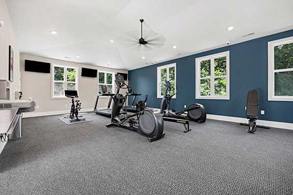 A fitness center with treadmills, elliptical machines, and other exercise equipment at Byron Lakes Apartments in Byron Center, MI
