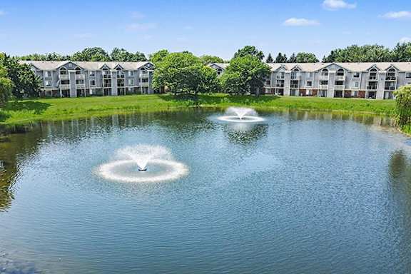 Fountains in the middle of a pond in front of apartment buildings at Byron Lakes Apartments in Byron Center, MI