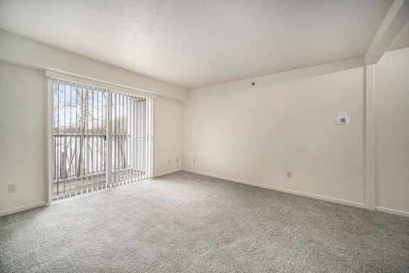 an empty living room with a sliding glass door to a balcony an empty living room with a sliding glass door to a balcony at Canal 2 Apartments in Lansing, MI