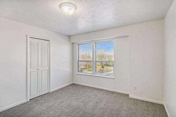Bedroom with large windows and a door to a closet Bedroom with large windows and a door to a closet at Canal 2 Apartments in Lansing, MI