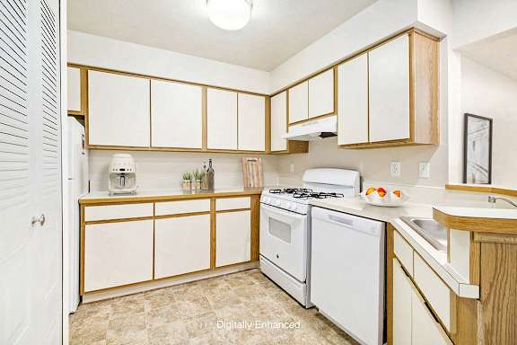 A kitchen with white appliances and wooden cabinets at Canal Club Apartments, Lansing, 48917