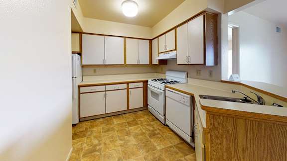 A kitchen with white appliances and wooden cabinets at Canal Club Apartments, Lansing, 48917