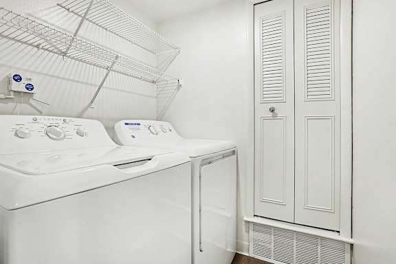 A white laundry room with a washing machine and dryer at Canal Club Apartments in Lansing, MI
