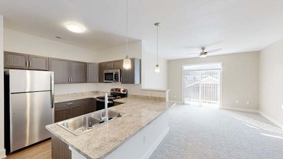 A modern kitchen with a stainless steel refrigerator and a countertop with a sink  at Chase Creek Apartment Homes in Huntsville, AL