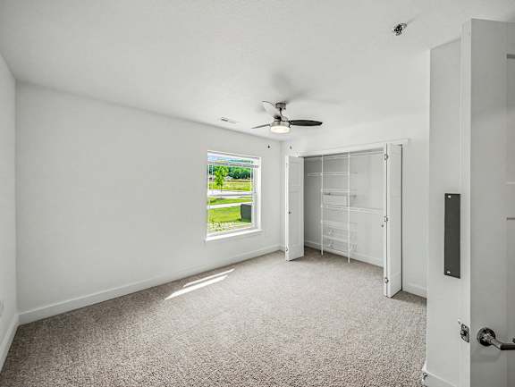 A bedroom with a ceiling fan and a large window showing a green lawn outside at Chase Creek Apartment Homes, Huntsville, AL, 35811