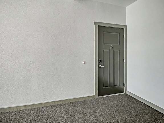 An apartment entryway with a grey door is in a hallway with carpet at Chase Creek Apartment Homes in Huntsville, AL