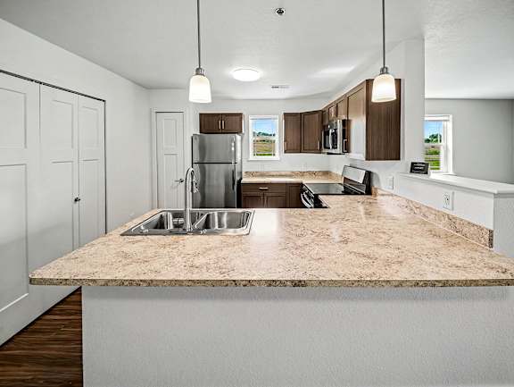 A kitchen with a breakfast bar, stainless steel appliances, and a window at Chase Creek Apartment Homes, Huntsville, AL, 35811