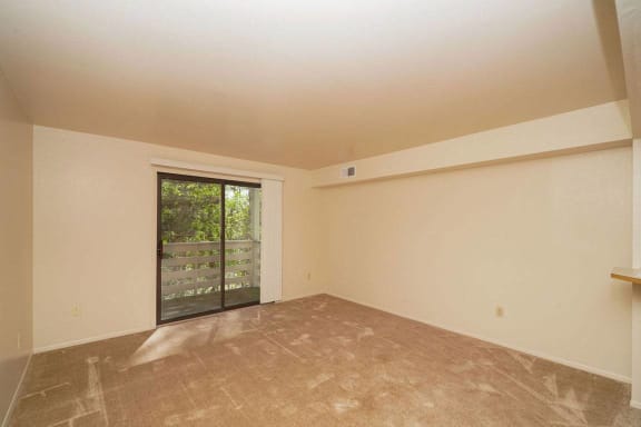 A living room with a slider to a balcony at Canal Club Apartments, Lansing, 48917