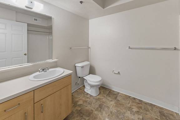 A bathroom with a toilet, sink, and mirror at Colonial Pointe at Fairview Apartments, Bellevue, NE, 68123