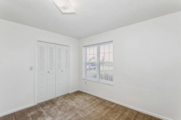 A bedroom with a window and a walk in closet at Colonial Pointe at Fairview Apartments, Bellevue, Nebraska