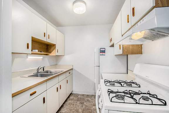A galley-style kitchen with a stove, refrigerator, and sink at Concord Place Apartments, Kalamazoo, MI
