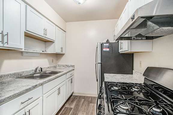 An upgraded kitchen with white cabinets and stainless steel appliances at Concord Place Apartments, Kalamazoo, 49009black gas stove.