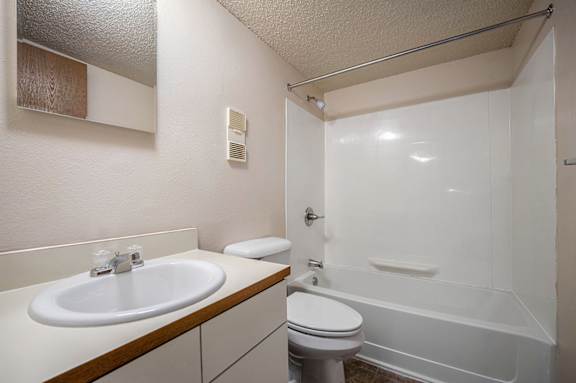 A bathroom with a toilet next to a sink and a bathtub at Concord Place Apartments, Kalamazoo, MI, 49009