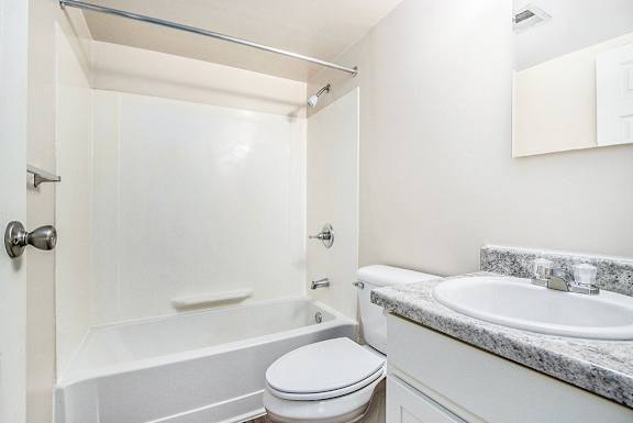 A white, upgraded bathroom with a toilet, sink, and bathtub at Concord Place Apartments, Kalamazoo, MI