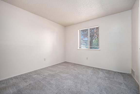 A bedroom with a window and carpeted floor at Concord Place Apartments, Kalamazoo, MI, 49009