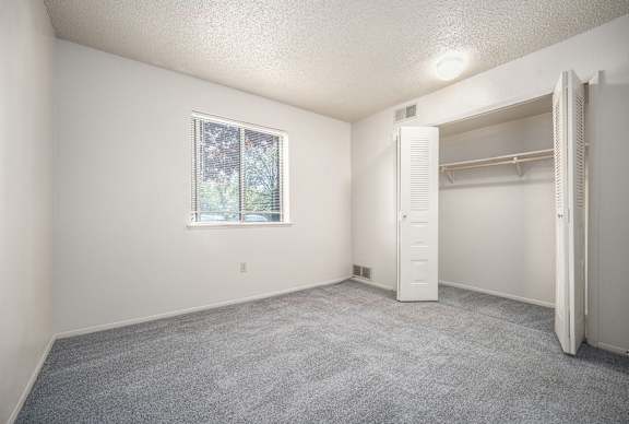 A bright bedroom with a window and a closet at Concord Place Apartments, Kalamazoo, MI, 49009