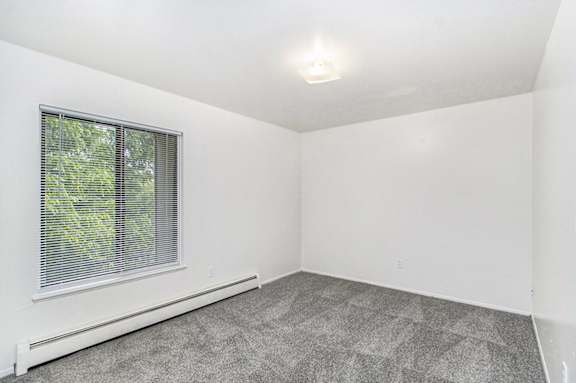 A spacious bedroom with a window and carpeted floor at Concord Place Apartments, Kalamazoo, MI