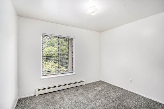 A bedroom with a window and plush carpeting at Concord Place Apartments, Kalamazoo, MI