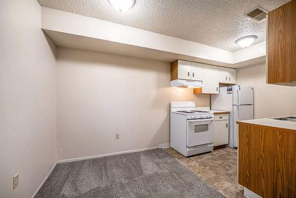 A dining area and kitchen with white appliances and wooden cabinets at Concord Place Apartments, Kalamazoo, MI, 49009