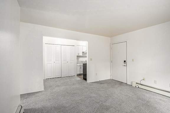 A living and dining room with a carpeted floor leading to a kitchen at Concord Place Apartments, Kalamazoo, MI