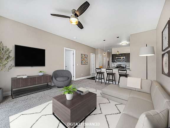 A living room with a grey armchair, a white sofa, a wooden coffee table A living room with a grey armchair, a white sofa, a wooden coffee table at Copper Creek Apartment Homes, Maize, Kansas