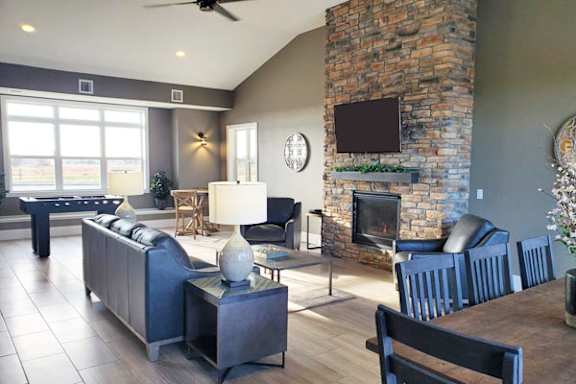 Open concept living room with stone fireplace and pool table at Copper Creek Homes Apartments, Kansas, 67101