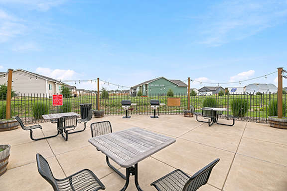Outdoor patio area with seating and grills at Copper Creek Homes Apartments, Maize