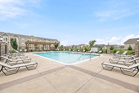 Resort style swimming pool with lounge chairs at Copper Creek Homes Apartments, Maize, KS 67101