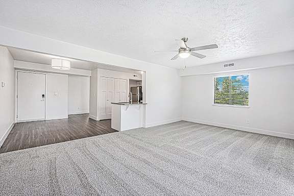 A living room with a ceiling fan and carpeted floor at The Crossings Apartments in Grand Rapids, MI