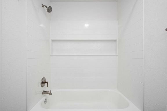 A white bathroom with a tub and shower at The Crossings Apartments, Grand Rapids