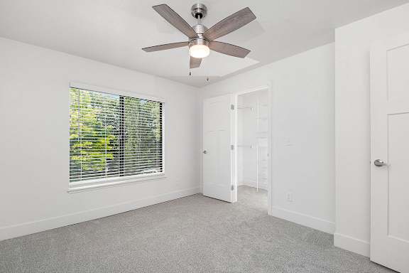 A bedroom with a ceiling fan and a window with blinds at The Crossings Apartments, Grand Rapids, 49508