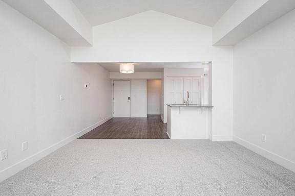 A large, empty living and dining room with a carpeted floor at The Crossings Apartments, Grand Rapids