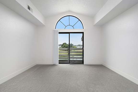A living room with a cathedral ceiling and large arched window and a view at The Crossings Apartments, Grand Rapids