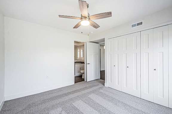 A bedroom with a ceiling fan and a carpeted floor at The Crossings Apartments in Grand Rapids, MI