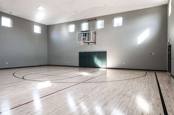 the inside of an empty gym with a basketball court and wood floors at Latitudes Apartments, Indiana