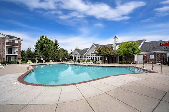 A large outdoor swimming pool surrounded by a concrete patio and buildingss at Towne Lakes Apartments, Grand Chute, 54913
